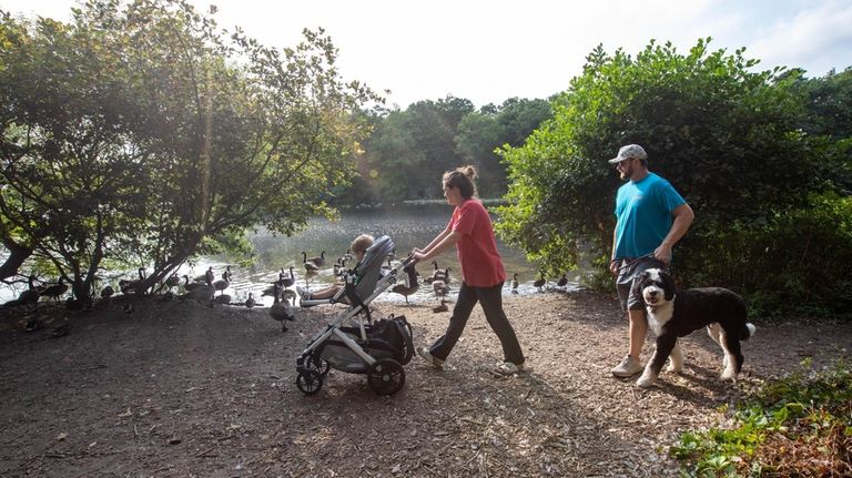 Visitors walk along the lake in the Massapequa Preserve in...