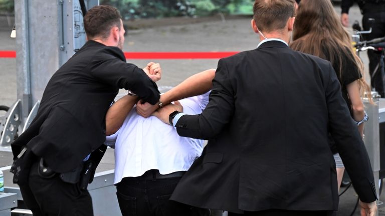 Bodyguards take away a man who allegedly carried out an...