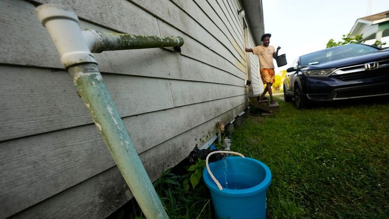 Leonard Kately collects buckets of water for his mother Lois...