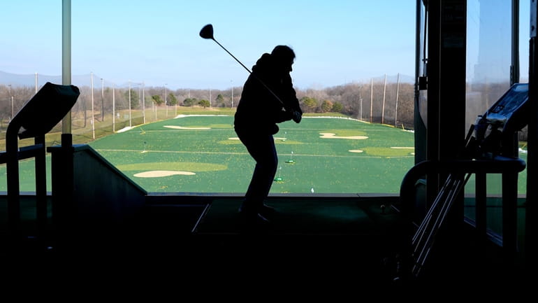 A golfer drives range balls on a warm day in...