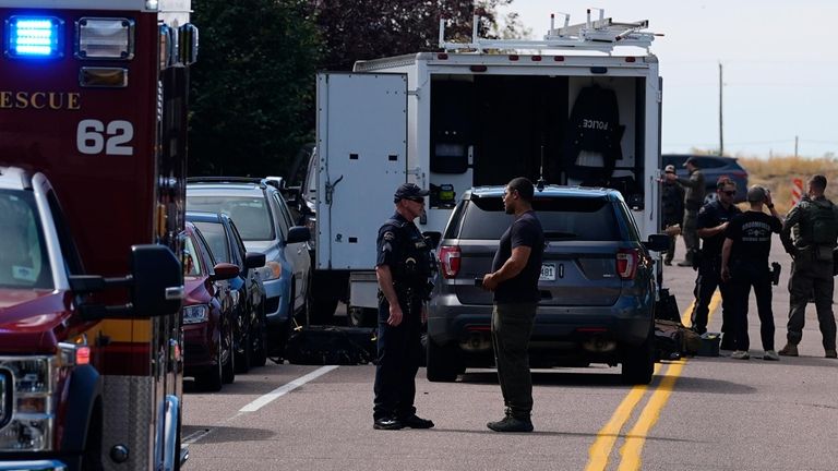 Law enforcement officers gather outside a building following a shooting...