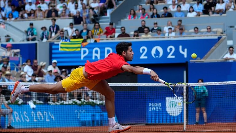 Carlos Alcaraz of Spain returns a shot to Felix Auger-Aliassime...