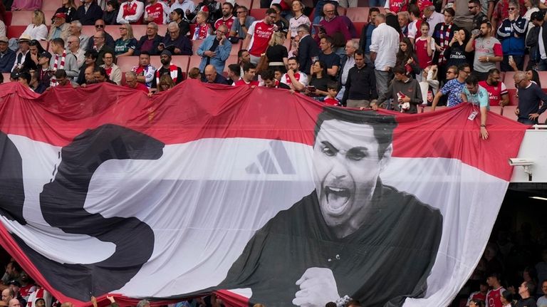 Fans show a banner with photo of Arsenal's manager Mikel...