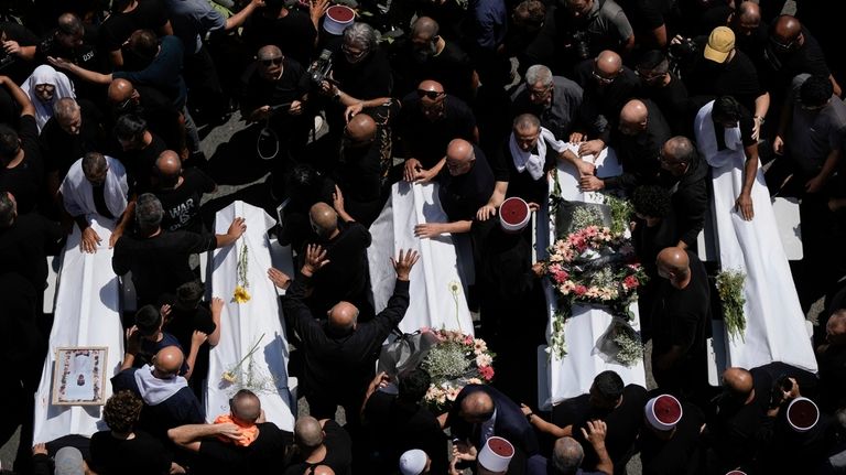 Mourners from the Druze minority surround the bodies of some...