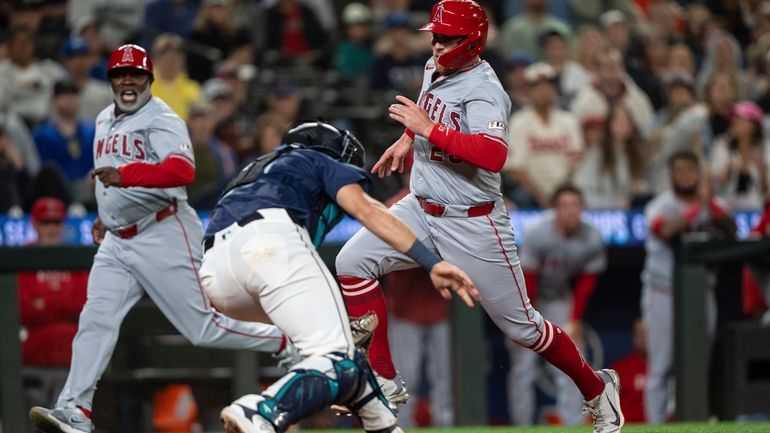 Los Angeles Angels' Brandon Drury, right, runs past Seattle Mariners...