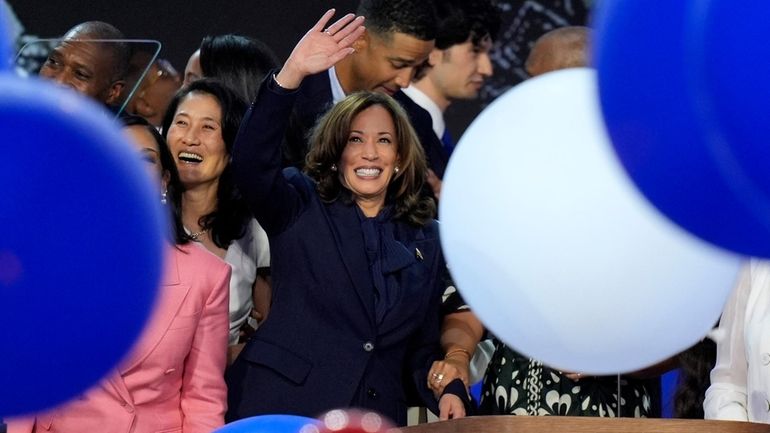 Democratic presidential nominee Vice President Kamala Harris waves surrounded by...