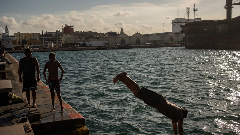 Pedro Murillo, a diver, jumps into the sea amid the...