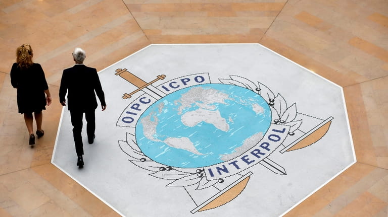 People walk on the Interpol logo at the international police...