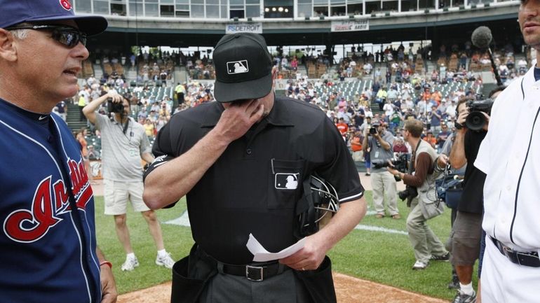 Home plate umpire Jim Joyce wipes tears during the exchange...