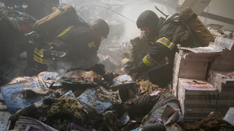 Firefighters recover bodies from under the rubble after a Russian...