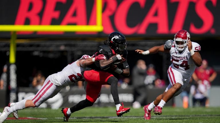 Oklahoma linebacker Danny Stutsman, left, tackles Cincinnati quarterback Emory Jones,...