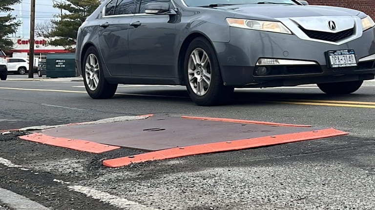 A metal plate covers the North Bellmore pothole in front...
