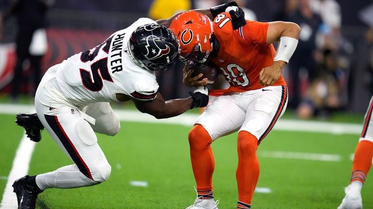 Chicago Bears quarterback Caleb Williams, right, is grabbed by Houston...