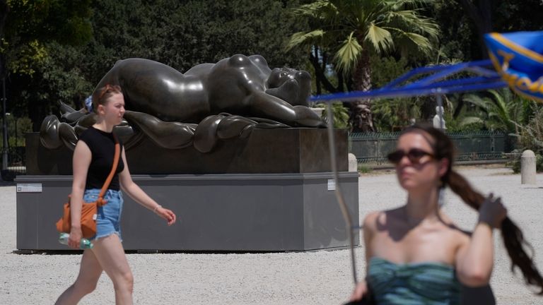 Tourists walk past Fernando Botero's "Sleeping Venus" sculpture at Rome's...