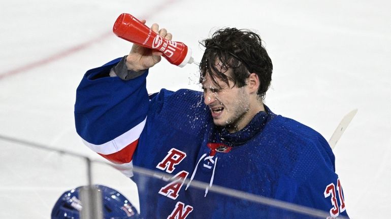 Rangers goaltender Igor Shesterkin splashes his face with water during...