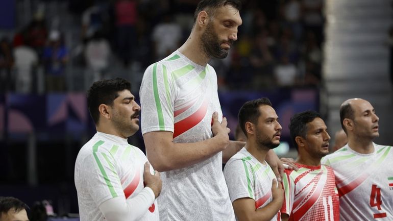 Irans's Morteza Mehrzadselakjani, fourth from right, stands with his teammates...