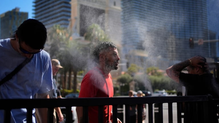 People cool off in misters along the Las Vegas Strip,...