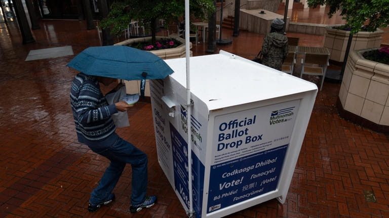 A person drops off their vote-by-mail ballot at a dropbox...