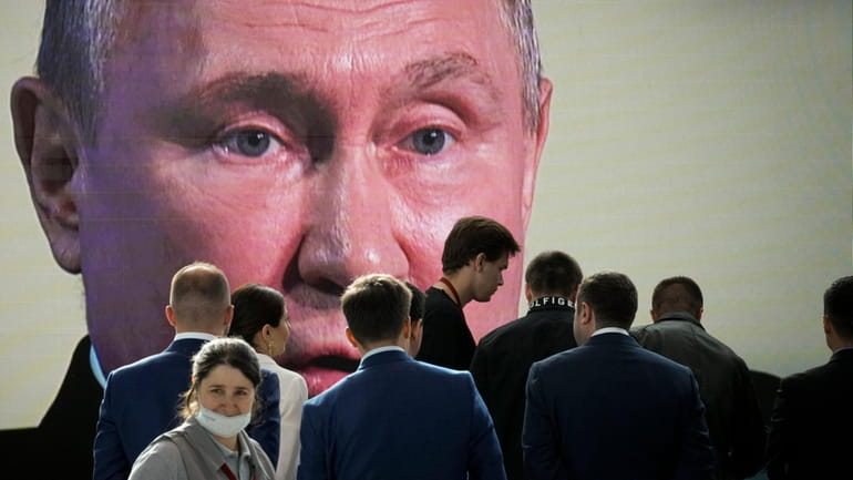 Participants watch Russian President Vladimir Putin's addressing a plenary session...