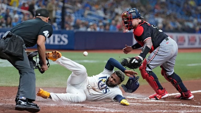 Tampa Bay Rays' Junior Caminero, center, scores on a fielder's...