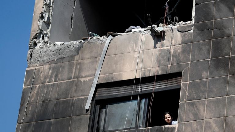 A girl looks out from a window of a residential...