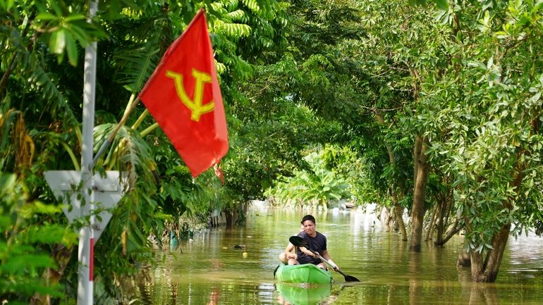 A man paddles a boat in the flood in the...