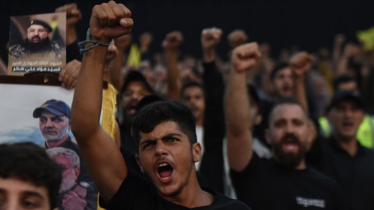 Supporters raise their fists and cheer as they watch a...