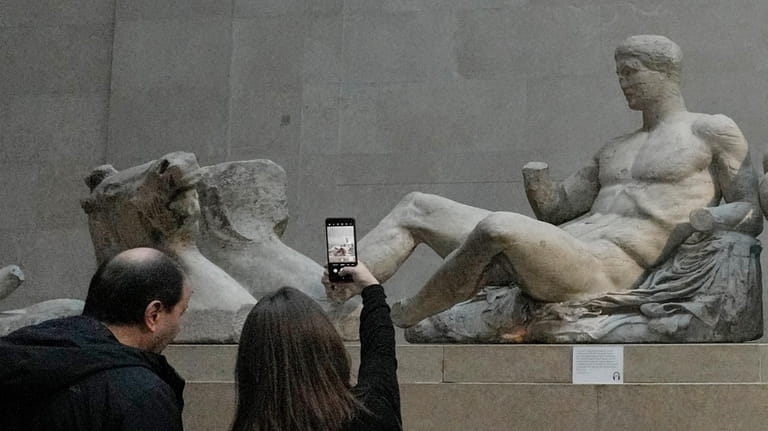 A visitor takes a picture of sculptures that are part...