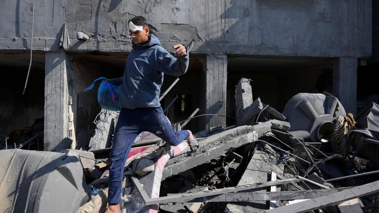 A Palestinian walks through the rubble of the Khatab family...