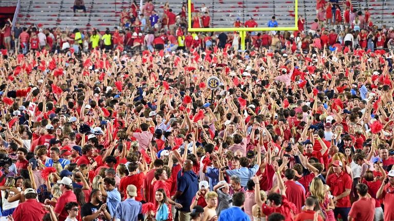 Mississippi fans celebrate on the field after an NCAA college...