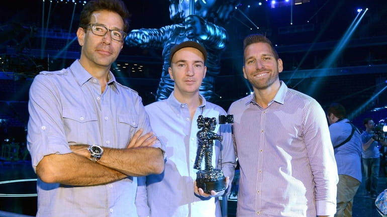 Artist KAWS, designer of the 2013 Moonman, center, with Executive...