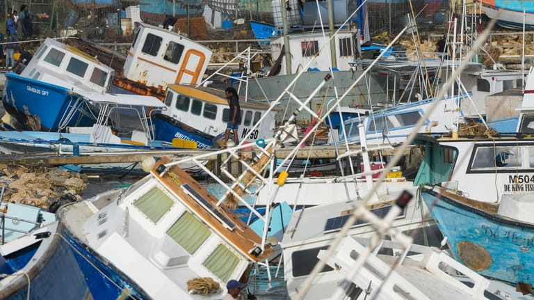 A fisherman looks at fishing vessels damaged by Hurricane Beryl...