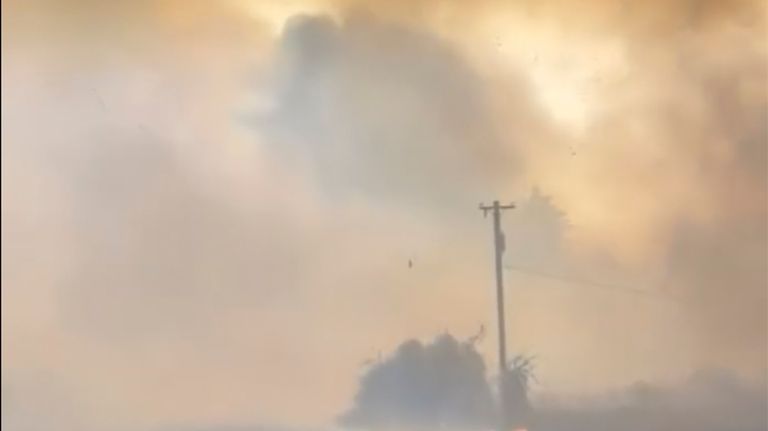 A motorist drives past the Gwen fire on Highway 3...