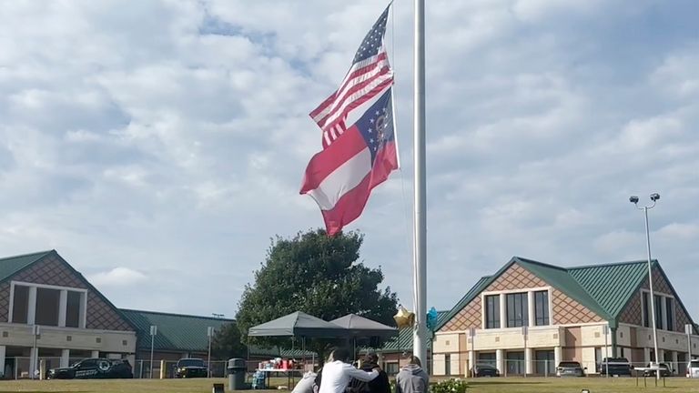 People gather at the flagpole outside the entrance to Apalachee...