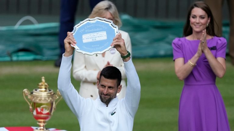 Novak Djokovic of Serbia hold up his runner-up trophy after...