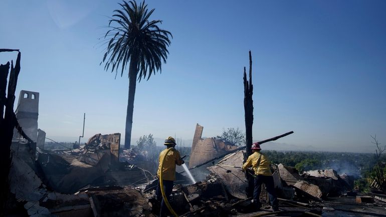 Firefighters mop up after the Edgehill fire in San Bernardino,...