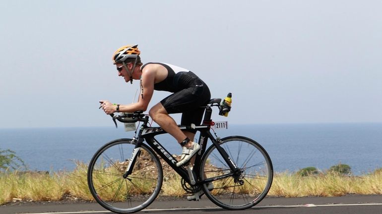 Adam Quinn competes in the biking portion of the 2013...