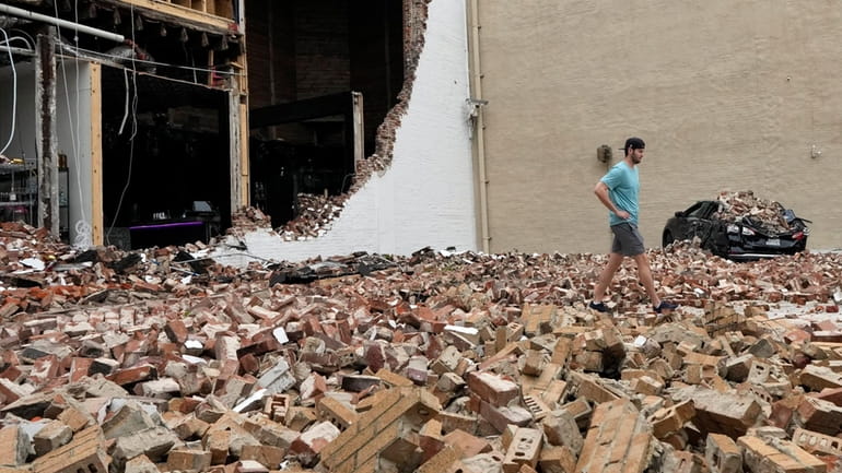 A man walks through fallen bricks from a damaged building...