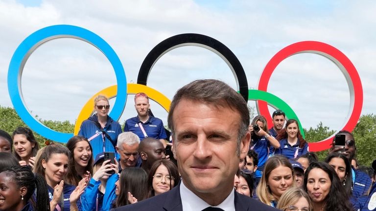 French President Emmanuel Macron leaves after posing with French athletes...