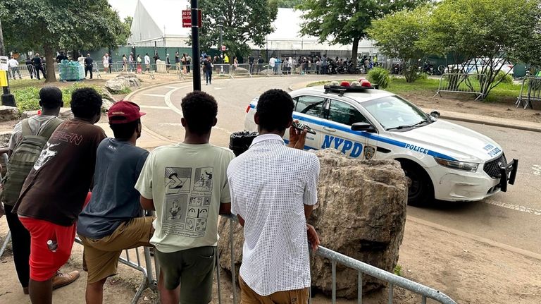 Asylum seekers watch police activity on the migrant shelter at...