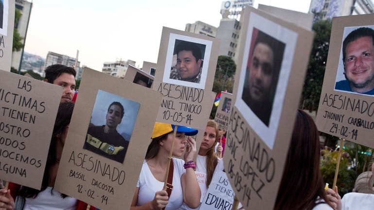 Demonstrators holds cardboard posters showing images of family and friends...