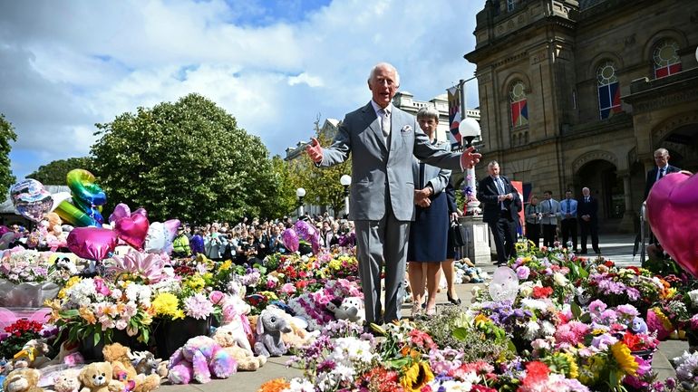 Britain's King Charles III looks at the tributes outside Southport...