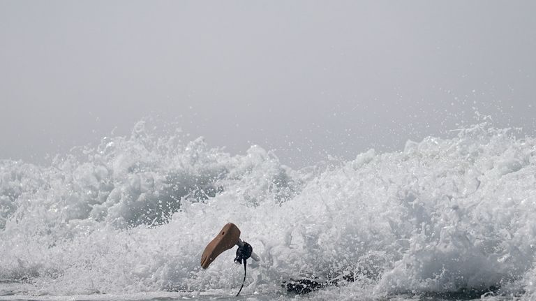 Chris Blowes, of Australia, duck-dives under a wave during the...