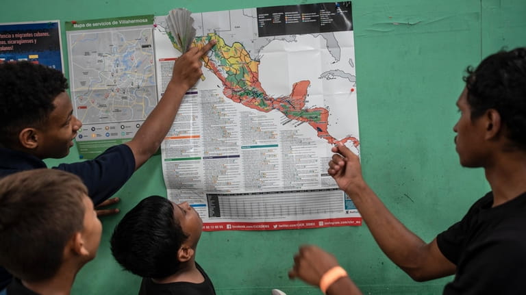 Teenager migrants look at a map of Mexico at the...
