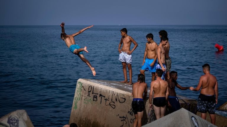 A man jumps into the sea on a breakwater in...