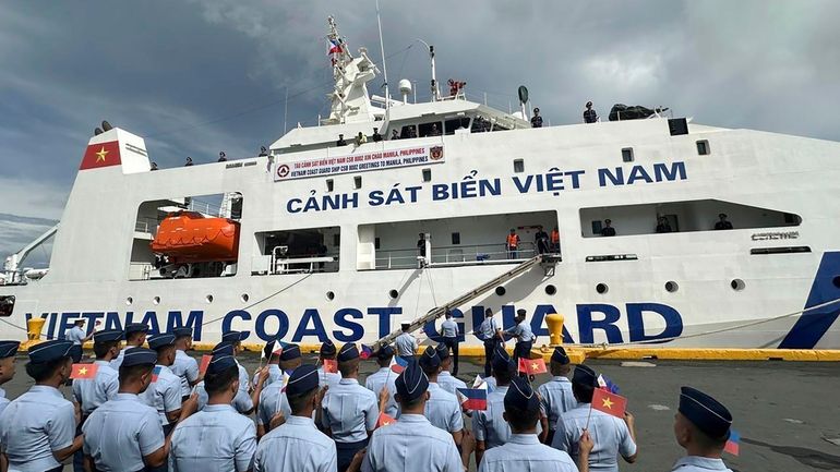 Philippine Coast Guard personnel wave Vietnamese and Filipino flags to...