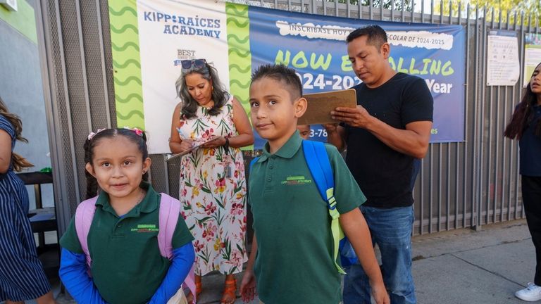 Roberto Garcia, right, signs in his children, Lily, 7, center,...