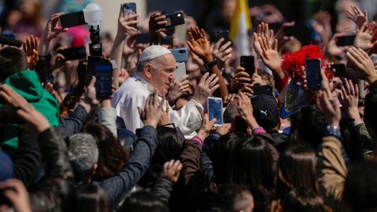 Pope Francis waves from his popemobile to the faithful gathered...