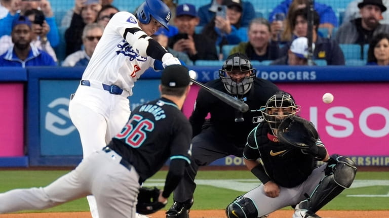 Los Angeles Dodgers' Shohei Ohtani, left, hits a single as...