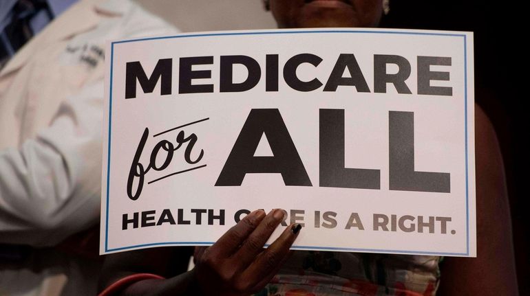 A member of the audience holds up a placard as...